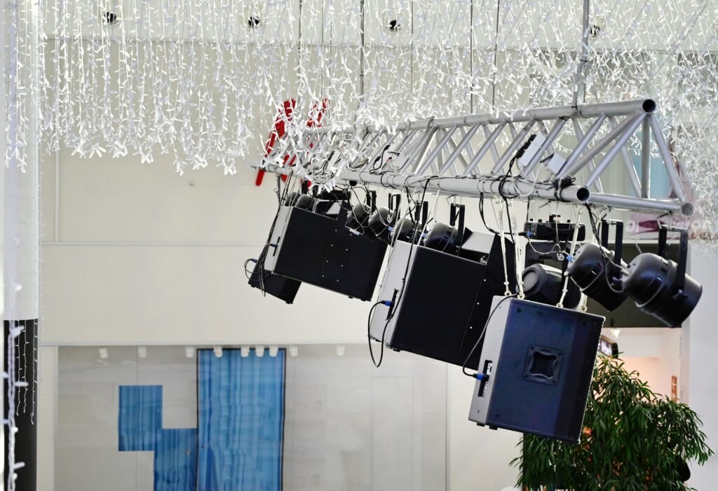 Modern audio equipment suspended from a truss in a spacious indoor venue during an event setup